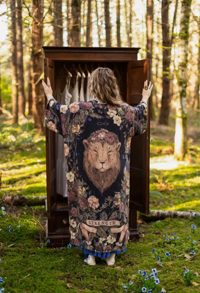 Person wearing a robe with a lion design in a forest setting